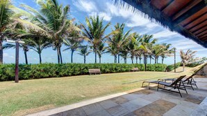 A paved outdoor area with palm trees, benches, and lounge chairs. - Scopa Beach #c1-200 - Seafront by Carpediem (Aquiraz)