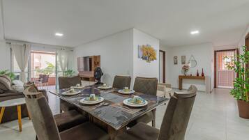 Un comedor con una mesa rectangular dispuesta para cuatro personas, rodeada de sillas tapizadas.