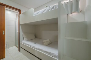 A bunk bed with a white mattress, a bedside table, and a wall-mounted light fixture. - Scopa Beach #c1-200 - Seafront by Carpediem (Aquiraz)