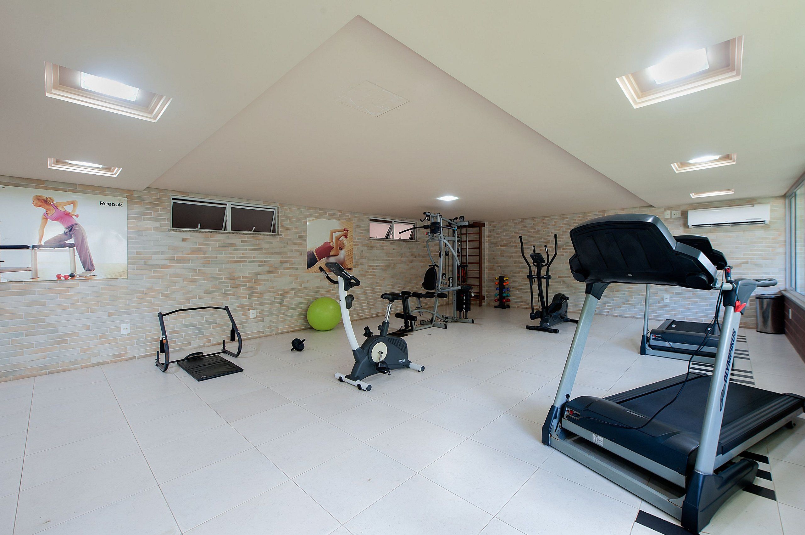 Un gimnasio con equipo de ejercicios como cintas de correr, una bicicleta estática y una máquina de remo.