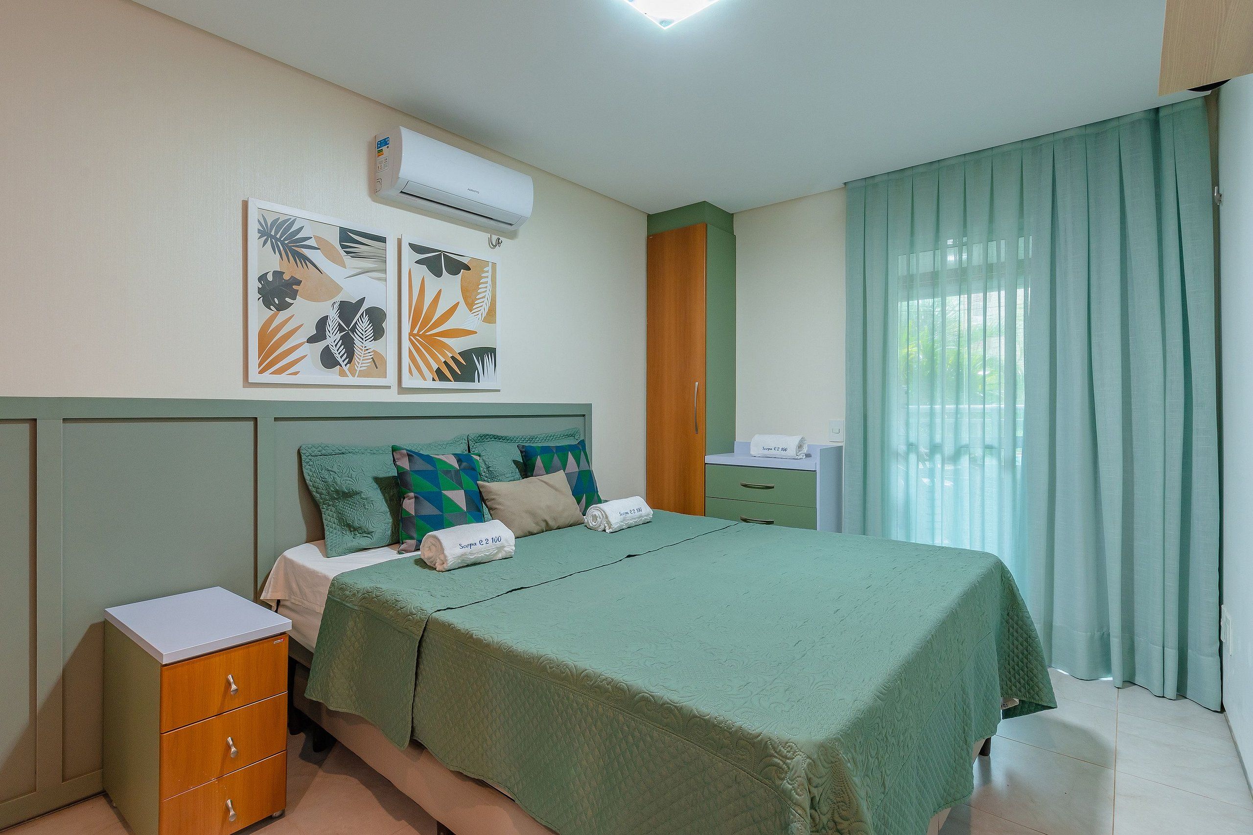 Habitación de hotel con cama, mesita de noche, armario y ventana con cortinas.