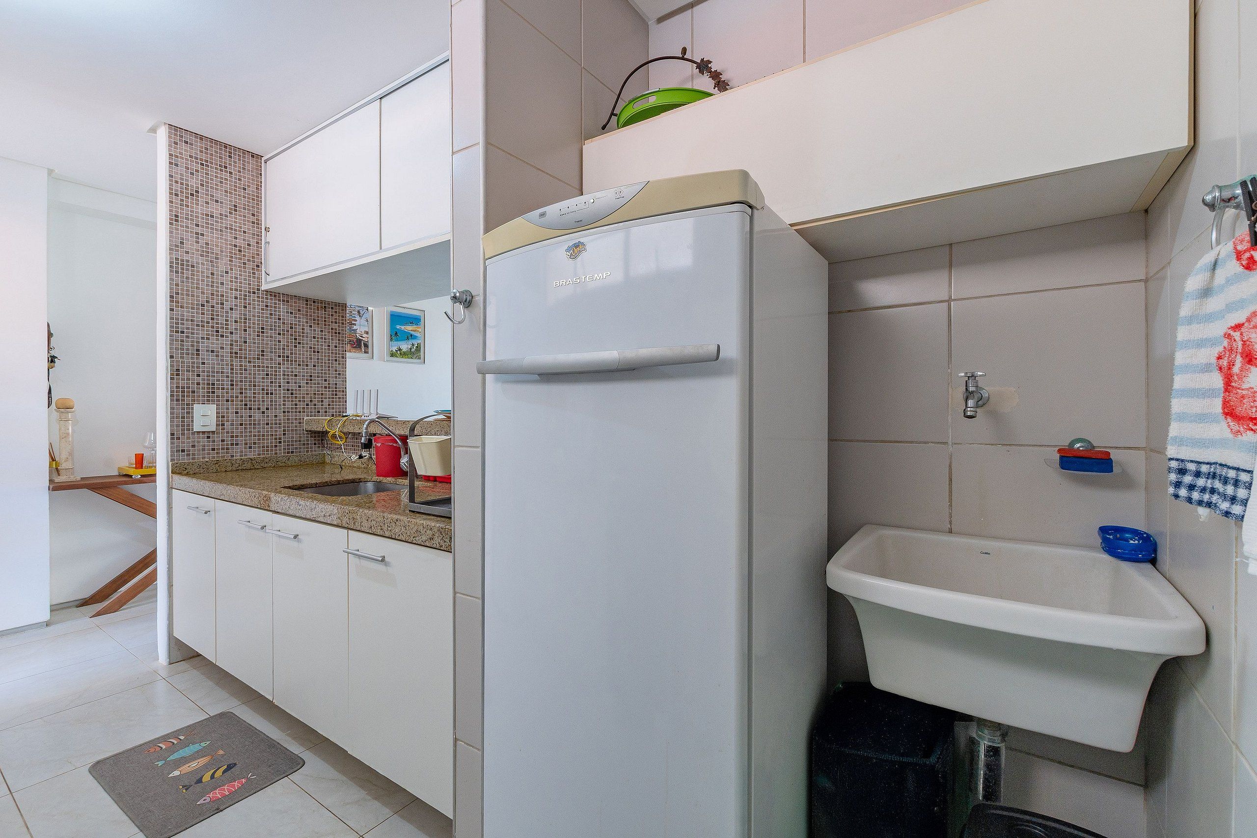 Una cocina con un refrigerador blanco, un lavamanos y un salpicadero de azulejos.