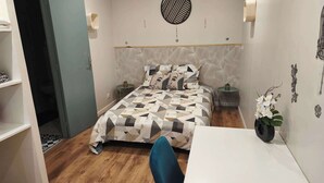 Ein Schlafzimmer mit einem bettenbezug mit geometrischem Muster, einer runden Wanddekoration und einer kleinen Pflanze auf dem Nachttisch.