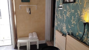 Una camera d'albergo con un letto, una panca con asciugamani, un tavolino e un quadro appeso al muro.