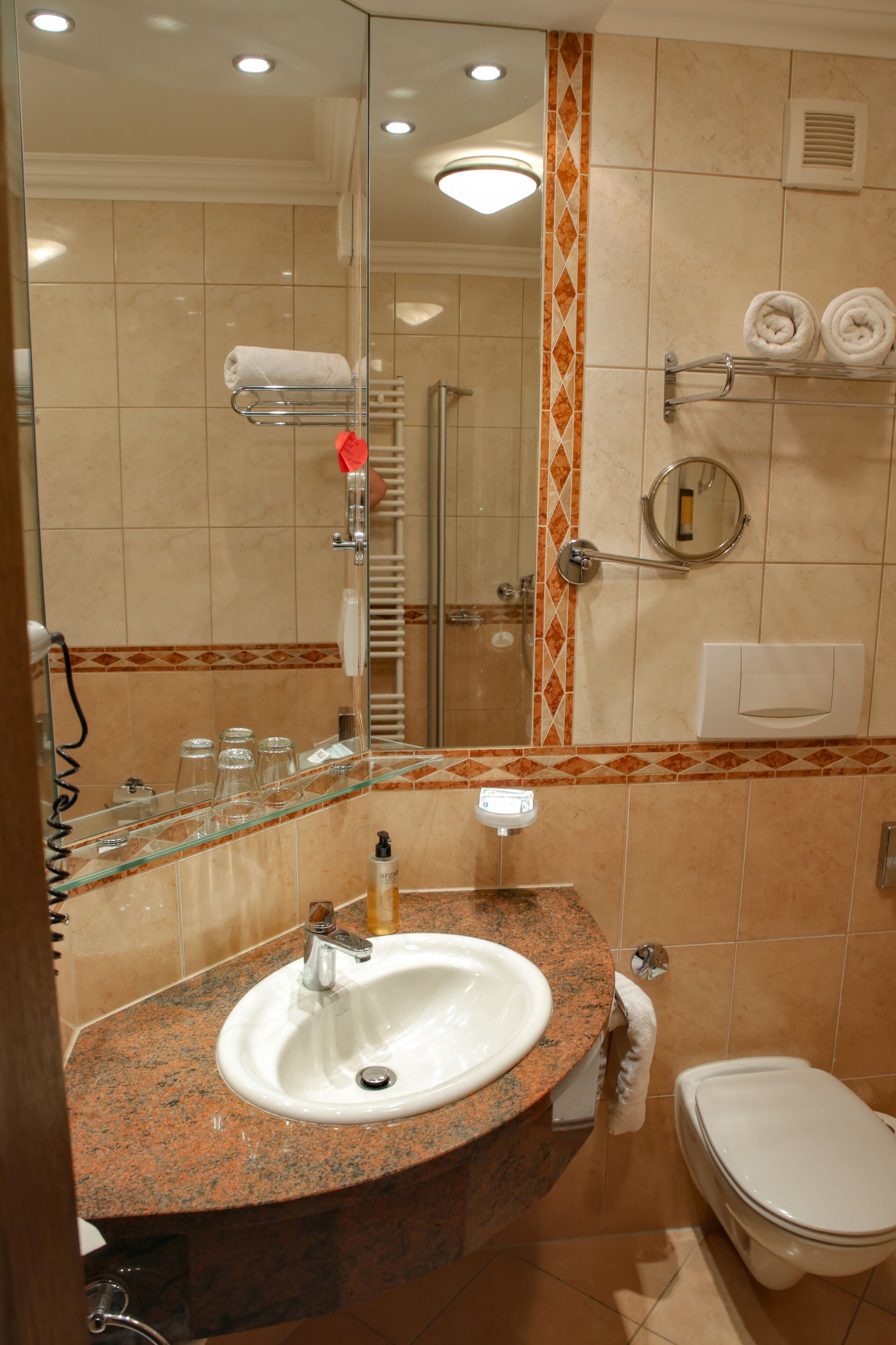Casa de banho com lavatório, espelho, porta-toalhas e sanita.