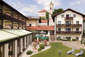 A hotel courtyard with outdoor seating, a bell tower, and a well-maintained garden. - Gräfliches Hotel Alte Post (Bad Birnbach)