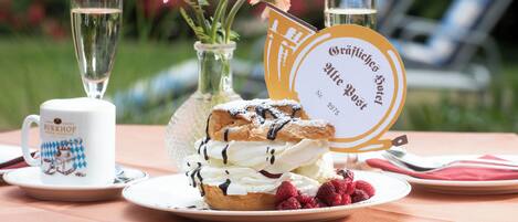 A table with a dessert, two glasses of a clear beverage, a mug, and a sign with text.