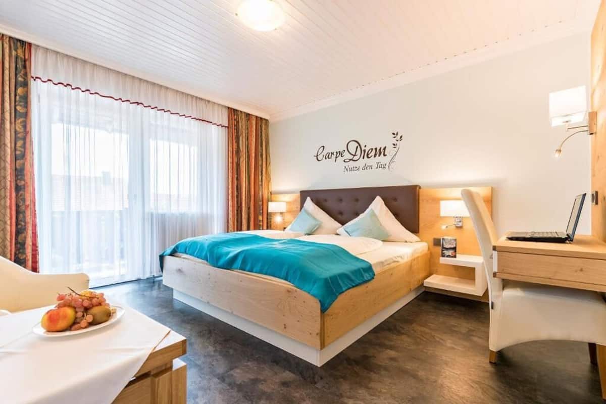 Una habitación de hotel con una cama, un escritorio y una computadora portátil.