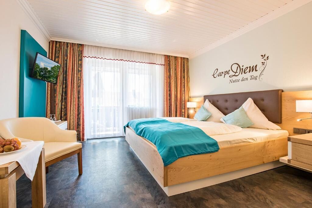 Quarto de hotel com uma cama, uma escrivaninha com uma fruteira, uma televisão e um quadro na parede.