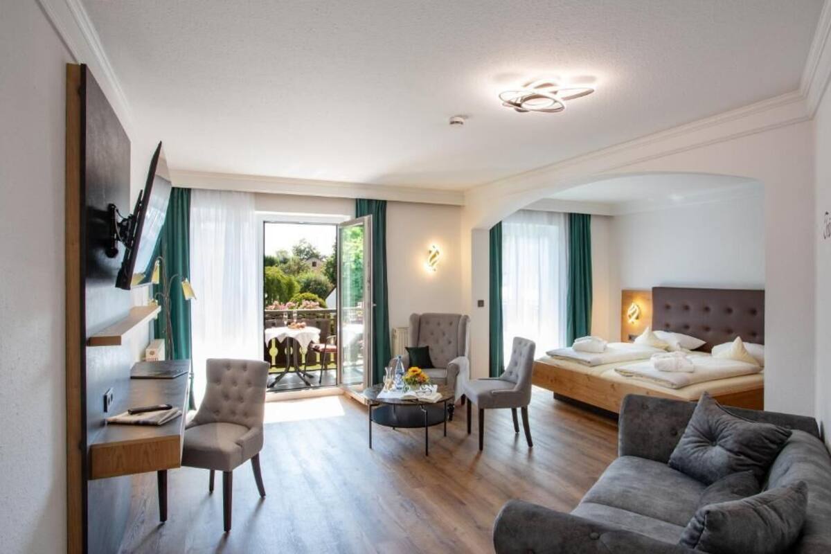Una habitación de hotel moderna con una cama, un sofá, un escritorio y un comedor con mesa y sillas.