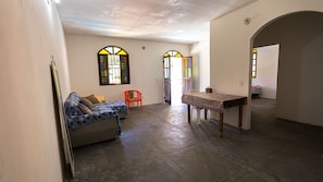 A room with a sofa, a red chair, a table, and two stained glass windows.