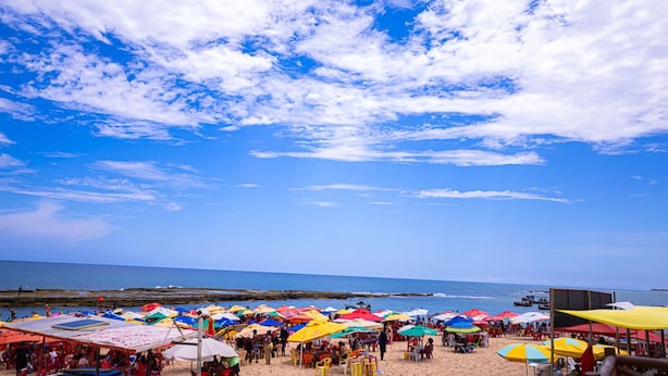 A beach with colorful umbrellas and people. - Casa com Piscina em Coqueiro de Arembepe (Camaçari)
