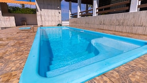A rectangular swimming pool with a tiled deck surrounding it. - Casa com Piscina em Coqueiro de Arembepe (Camaçari)