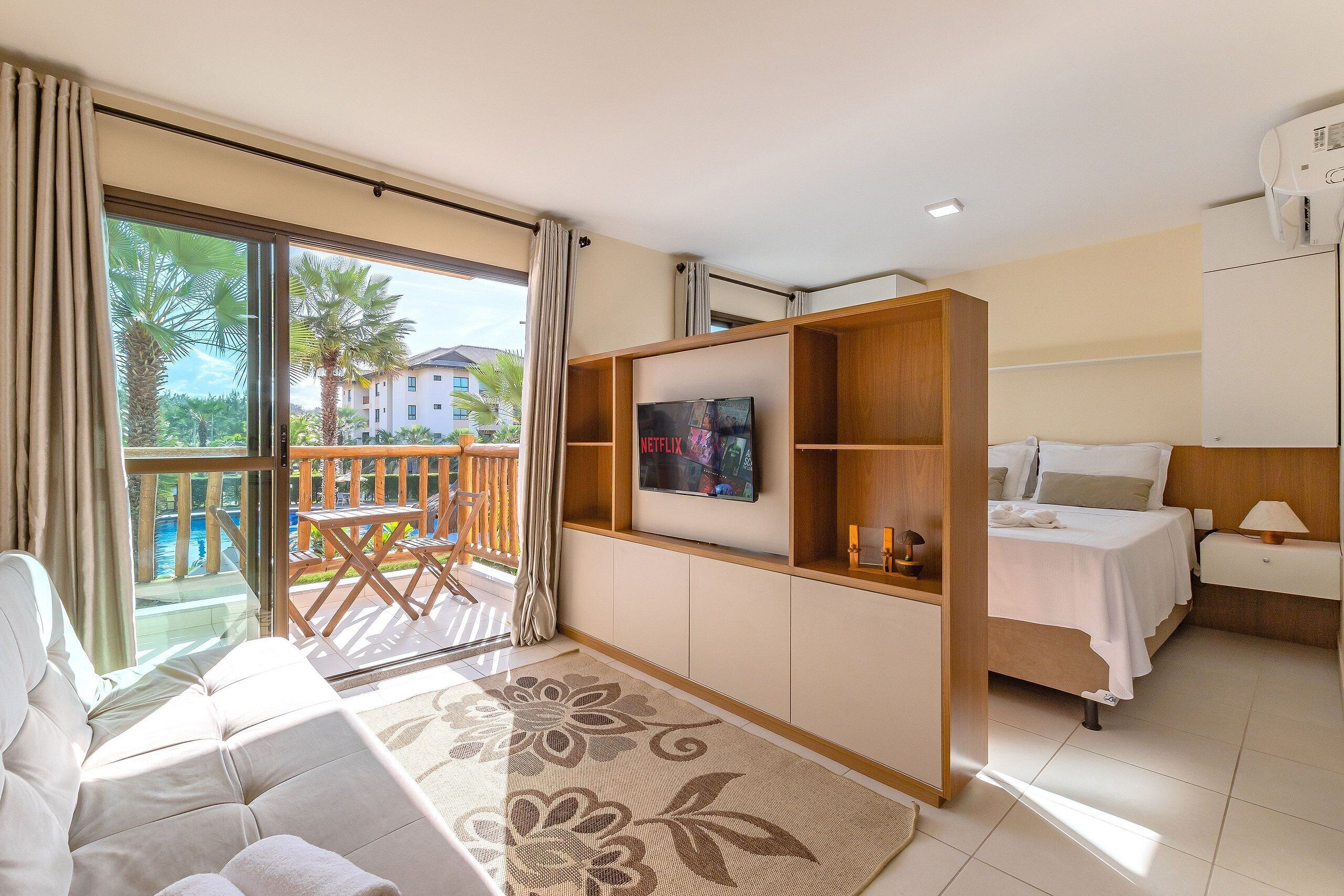 Une chambre d’hôtel moderne dotée d’un balcon, d’une télévision à écran plat, d’un lit et d’un canapé.