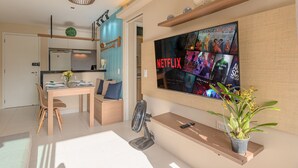 A modern living room with a dining area, a TV mounted on the wall, and a potted plant. - VG Sun #310 - Quadruple Apartment by Carpediem (Caucaia)