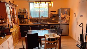 A modern kitchen with wooden cabinets, a glass dining table, and a built-in oven.