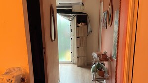 A hallway with a wooden floor, a white air conditioning unit mounted on the wall, and a door leading to another room.