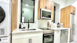 A modern kitchen with a built-in oven, microwave, and stainless steel sink. - Hudson Yards Modern 1 bedroom (New York)
