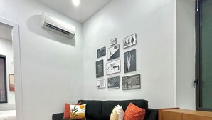 A modern living room with a black sofa, colorful cushions, a patterned rug, and a wall adorned with framed pictures. - Hudson Yards Modern 1 bedroom (New York)