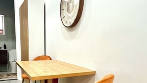 A dining area with a wooden table and orange chairs, a white cabinet, and a decorative wall piece. - Hudson Yards Modern 1 bedroom (New York)