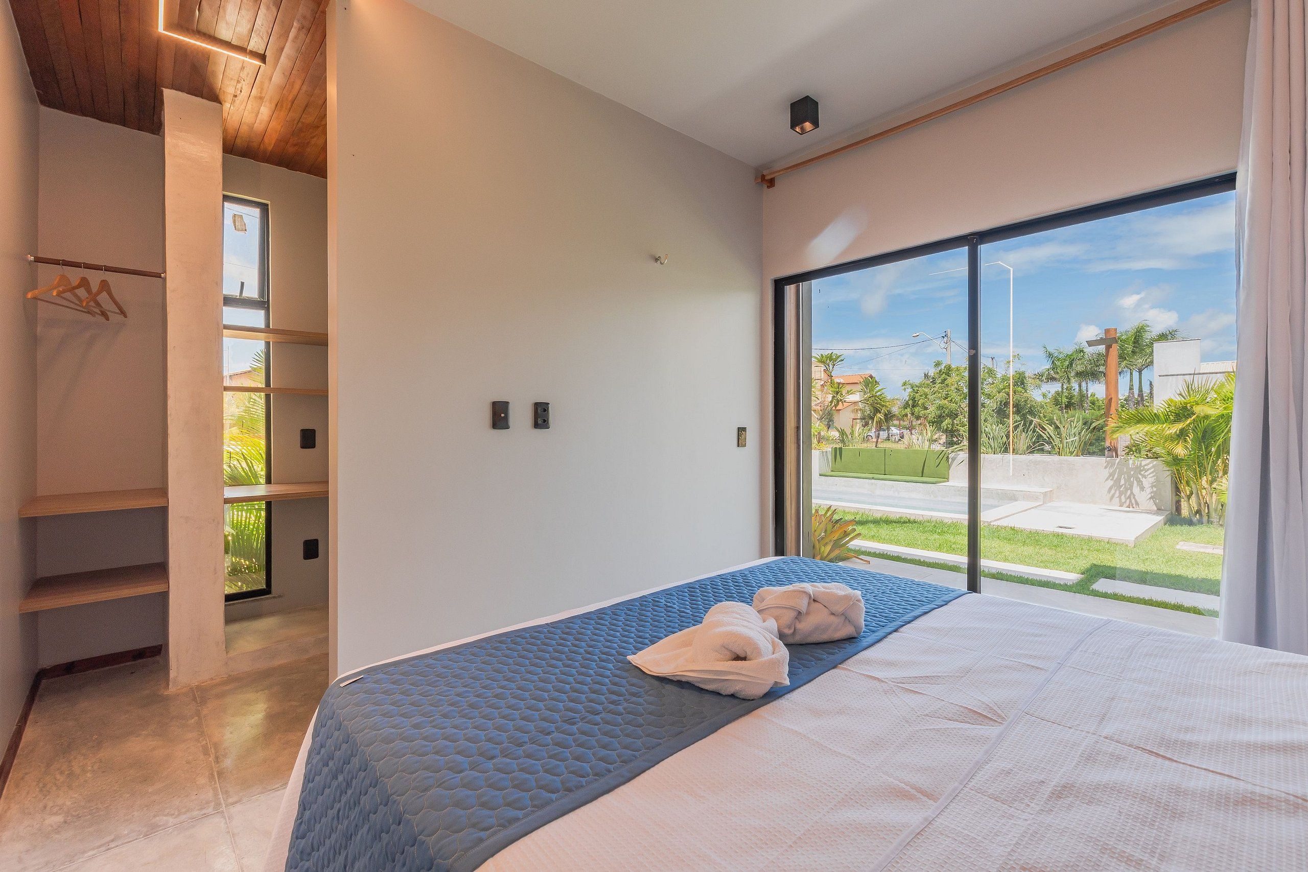 Un dormitorio con un ventanal grande, una cama, un armario y vistas al exterior.