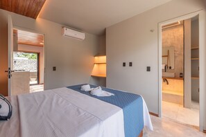 A hotel room with a bed, a bathroom with a mirror, and a door leading to an outdoor area. - Summerville #117 - Luxury in Cumbuco by Carpediem (Caucaia)