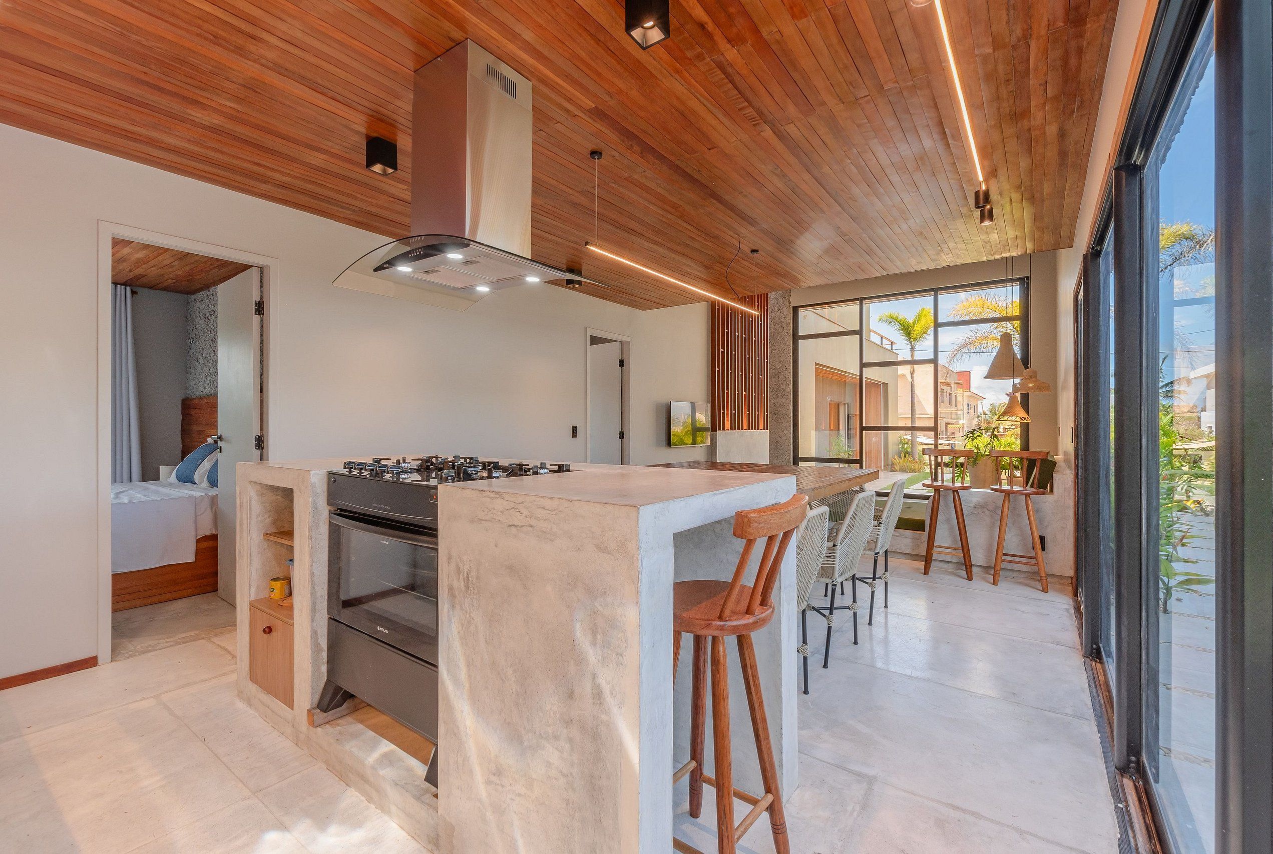 Una cocina moderna con una isla central, techo de madera y ventanas amplias.