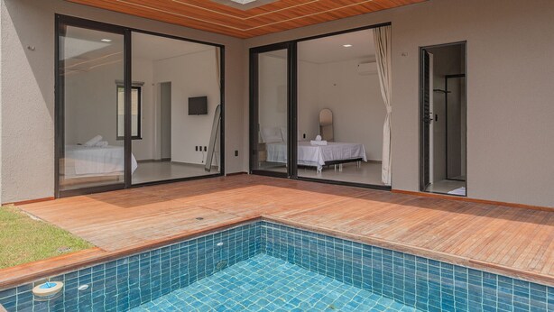 Een moderne hotelkamer met een grote glazen schuifdeur, een houten terras en een zwembadje.