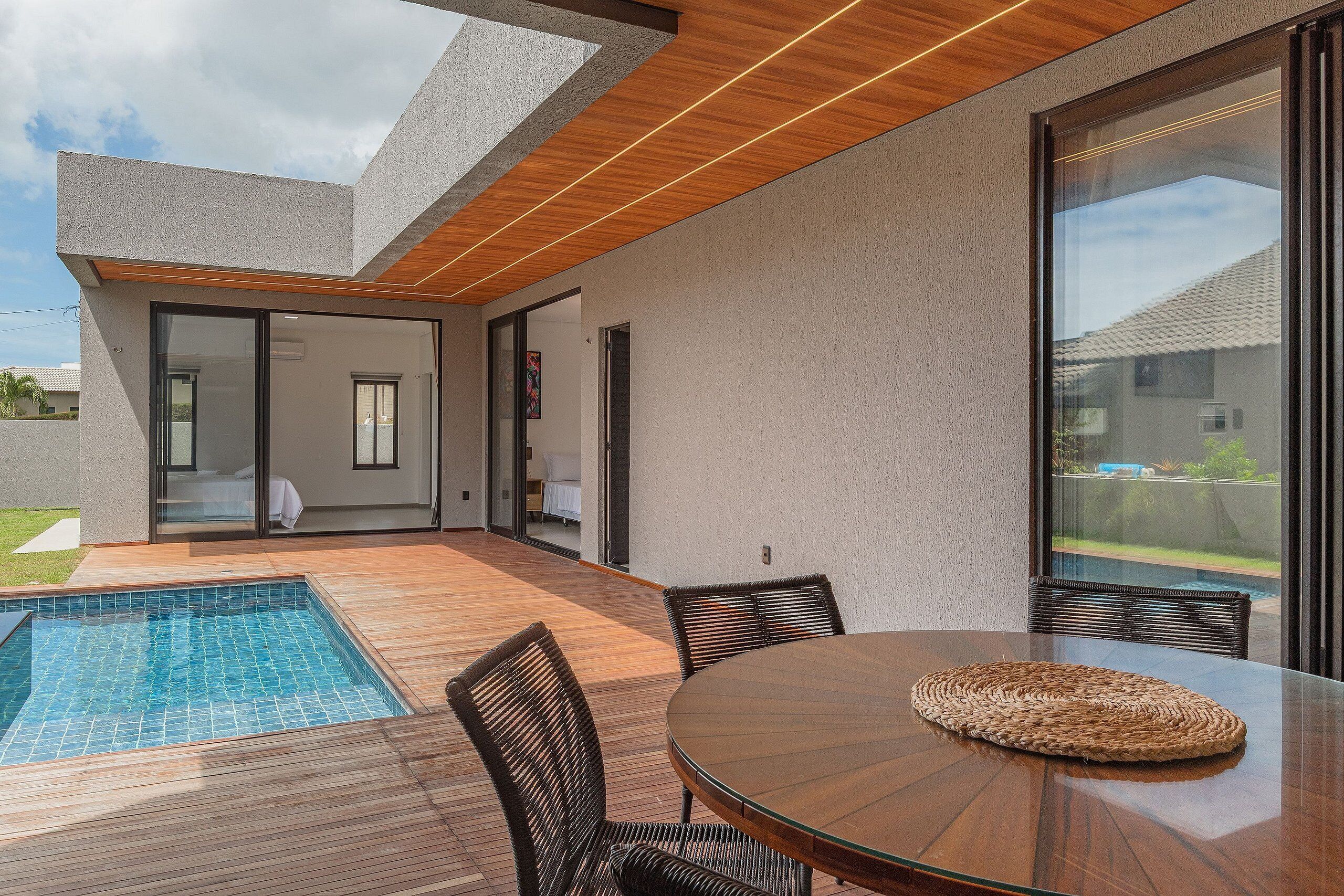 Un espacio exterior moderno con piscina, mesa y sillas para comer.
