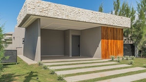 Een modern gebouw met een gevel van natuursteen, een overdekte ingang en een verzorgd gazon met een pad van stenen.