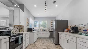 A modern kitchen with white cabinetry, stainless steel appliances, and a wooden floor. - Beach Bungalow w/ Pool & Hot Tub. Casinos nearby! (Biloxi)