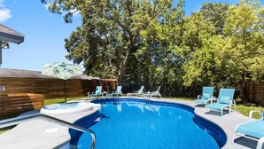 A swimming pool with lounge chairs and a wooden fence in the background. - Beach Bungalow w/ Pool & Hot Tub. Casinos nearby! (Biloxi)