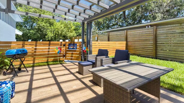 An outdoor patio with a covered seating area, a grill, and a wooden fence. - Beach Bungalow w/ Pool & Hot Tub. Casinos nearby! (Biloxi)