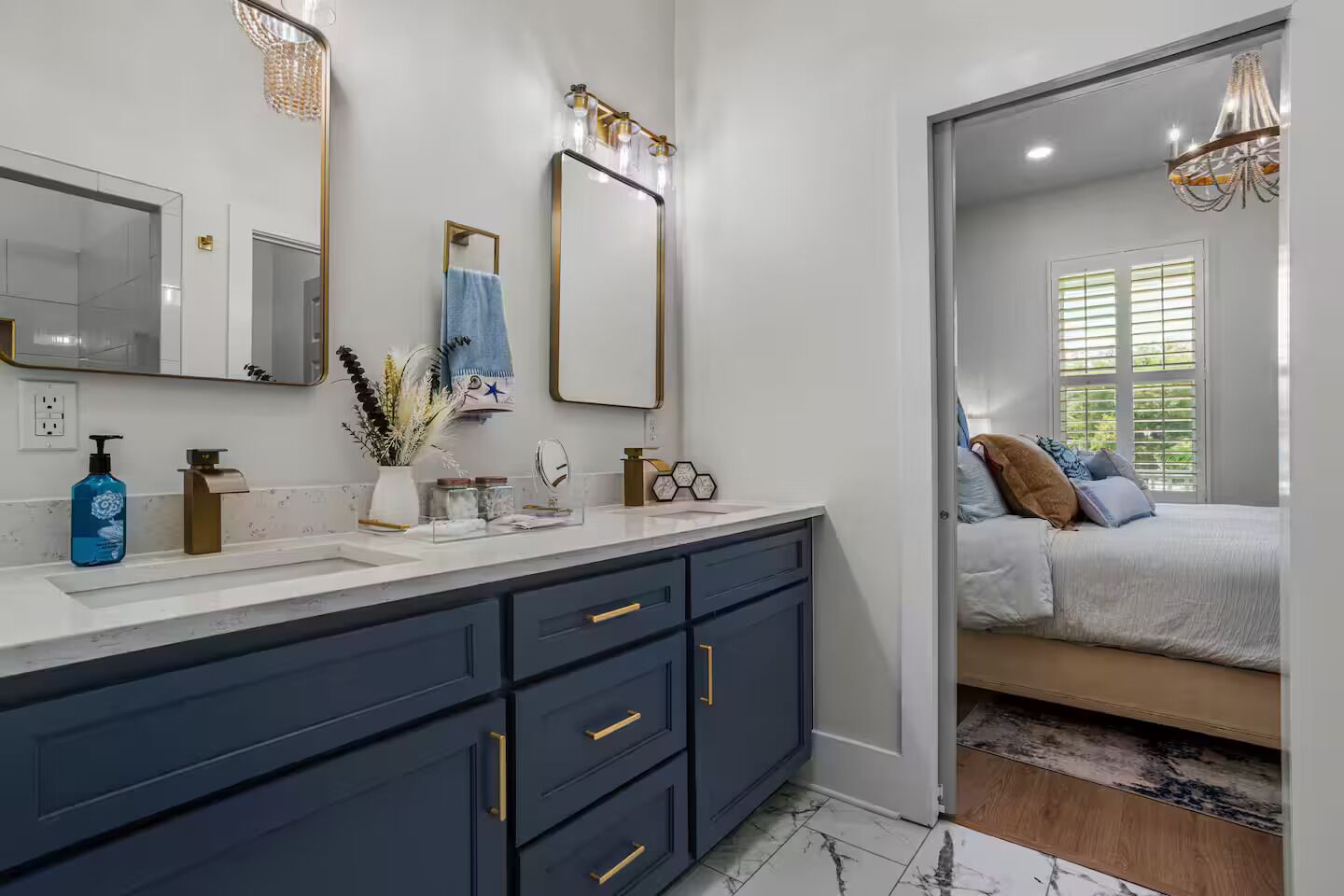 A modern bathroom with dark blue cabinets, a white countertop, and a large mirror.