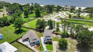 Vista aerea di una zona residenziale costiera con case, una spiaggia e un parco con sentieri.