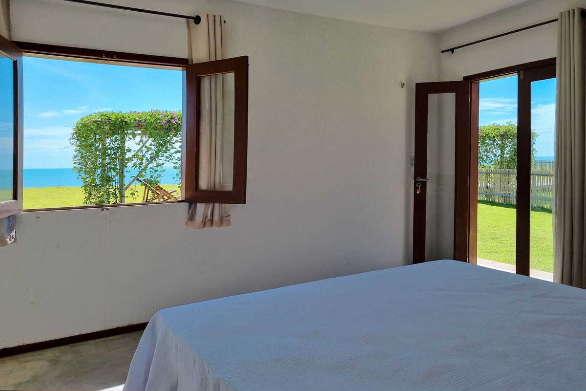 Una habitación con cama, ventana con cortinas y vista al mar.