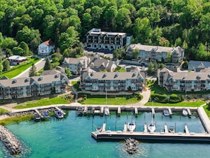 A marina with boats docked, surrounded by multi-story buildings with balconies, set in a lush green area.