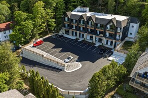 Ein mehrstöckiges Hotel mit Parkplatz, umgeben von Bäumen.