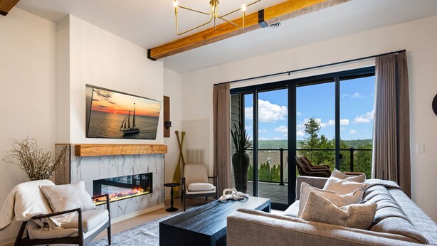 A modern living room with a fireplace, a sofa, a chair, and a large window with a view. - Luna View | Bay Views, Walk to Beach & Downtown Sister Bay (Sister Bay)
