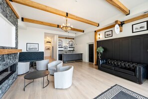 Ein modernes Wohnzimmer mit Kamin, einem schwarzen Ledersofa und einer Chandelier.