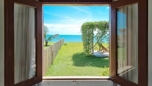 A view through an open window of a grassy area with a wooden fence, a tree, and a clear blue sky. - Beach Front Villas - House by the sea by Carpediem (Aracati)