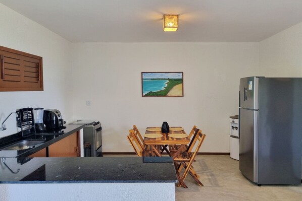 A compact kitchen with a dining table, chairs, a refrigerator, a coffee maker, and a toaster. - Beach Front Villas - House by the sea by Carpediem (Aracati)