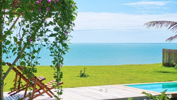 A wooden deck with a pool, a grassy lawn, and a view of the sea. - Beach Front Villas - House by the sea by Carpediem (Aracati)