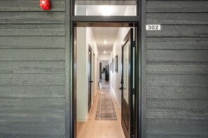 A hallway with wooden walls, a number '302' sign, and a red fire alarm. - Luna View | Top-Floor Water Views & Covered Patio in Sister Bay (Sister Bay)