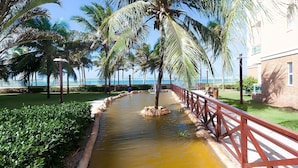 A landscaped area with a water feature, palm trees, and a red railing.