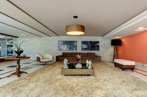 Ein modernes Wohnzimmer mit Couch, Sessel, Teppich und einem Couchtisch in der Mitte.