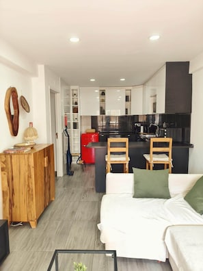 Un salon moderne avec un canapé, une table basse et un coin cuisine à l’arrière-plan.