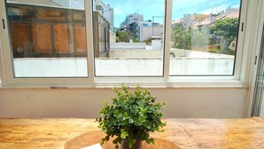Et værelse med et stort vindue, et træbord og en potteplante.