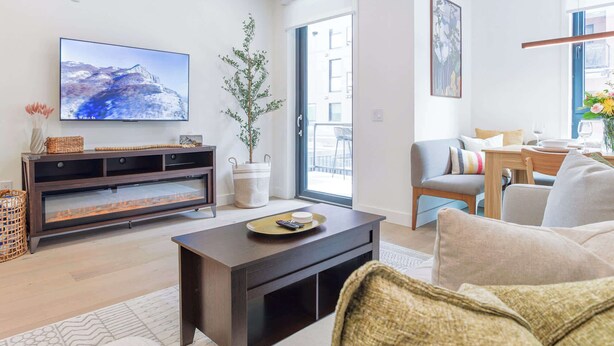 Una sala de estar moderna con una televisión de pantalla plana, chimenea, sofá, comedor y un ventanal grande.