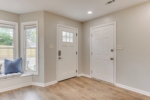 Une pièce avec un coin fenêtre, deux portes blanches et un plancher en bois.